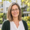Porträt von Claudia Reichert, Verwalterin einer Eigentümergemeinschaft, vor einem Mehrfamilienhaus