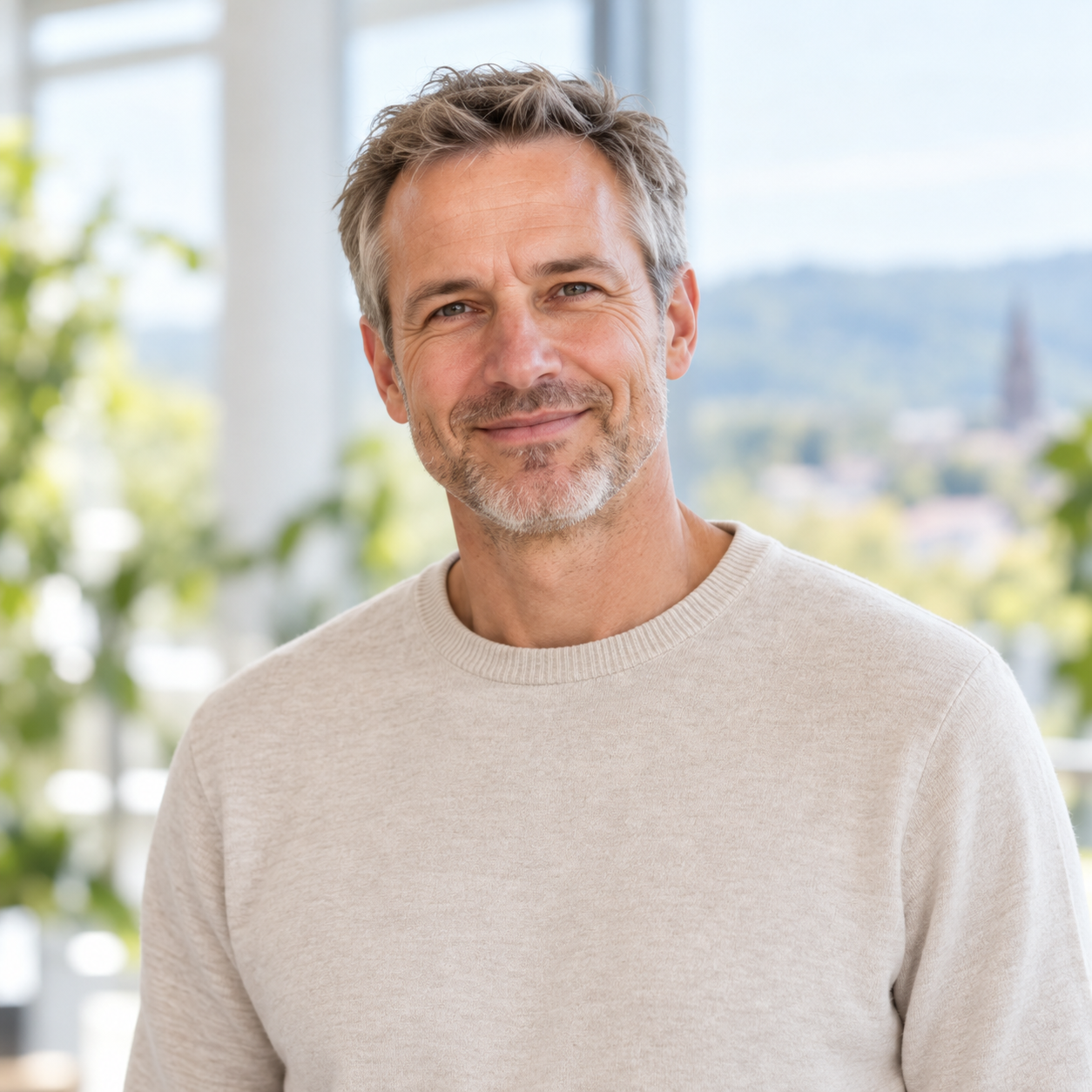 Porträt von Michael Kern, Inhaber und Energieberater, vor dem Fenster mit Blick auf Freiburg